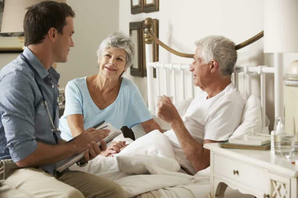 Male palliative care specialist interacting with senior male patient and his family