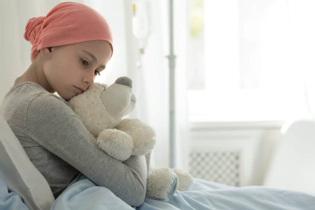 a palliative care female patient with cancer holding her stuffed toy in the hospital bed