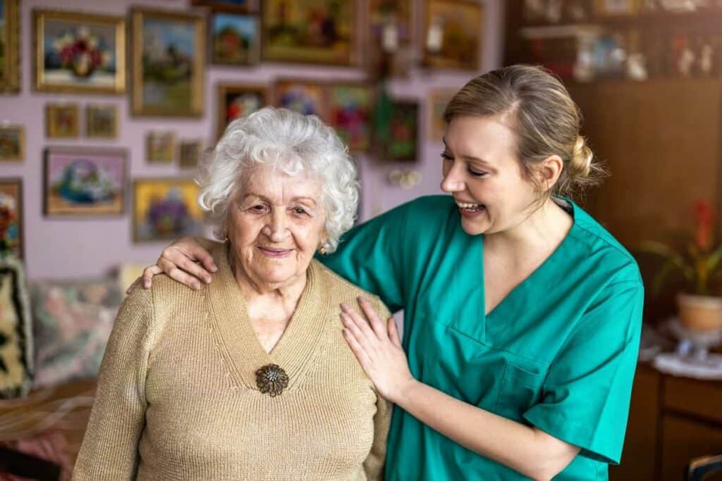 A caregiver touching the shoulders of a female senior resident while smiling - nursing homes Sparks.