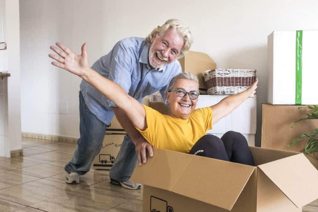 A senior couple happily moving boxes on the floor as they relocate to one of the assisted living facilities in Sparks NV.