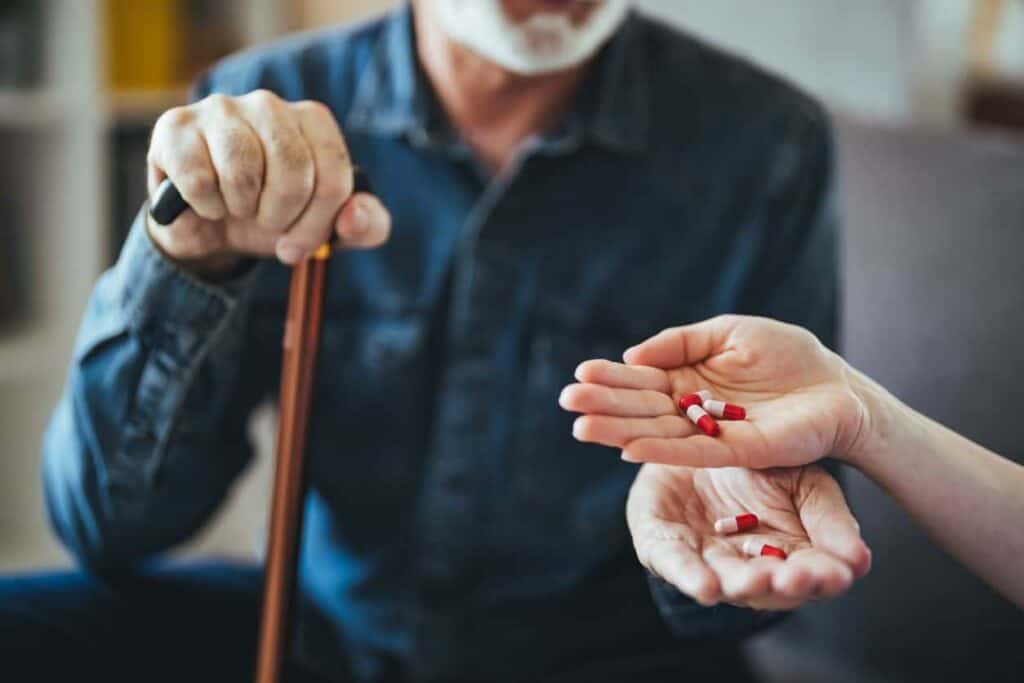Caregiver giving medication to senior - nursing home hiring