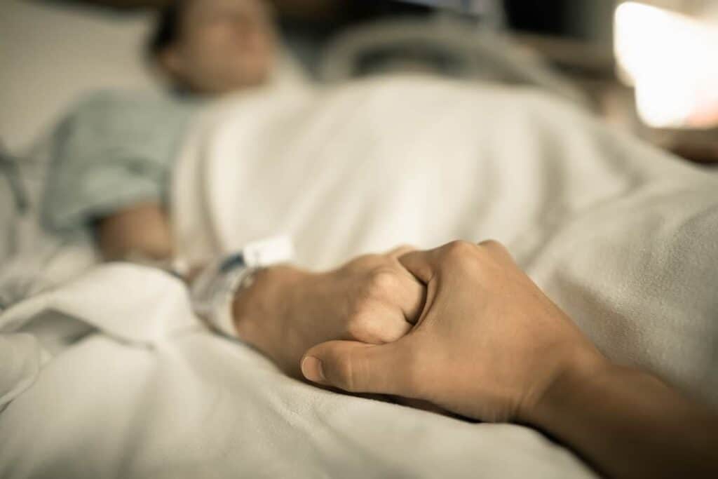 what happens in hospice - man holding hands with an elderly woman who is in hospice