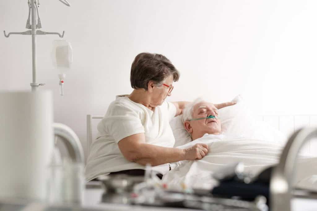 a woman staying by her husband's side as he starts showing signs of dying