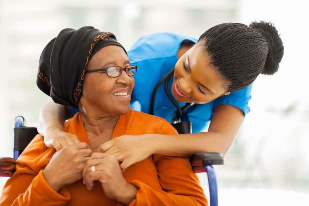 A senior patient with a nurse holding hands.
