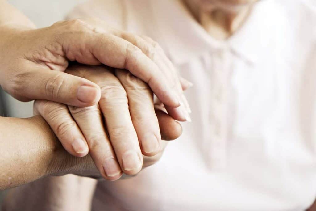 A close up of a healthcare worker’s hand holding the patient’s.