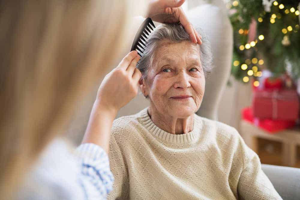 caregiver combing the hair of an elderly woman in hospice
