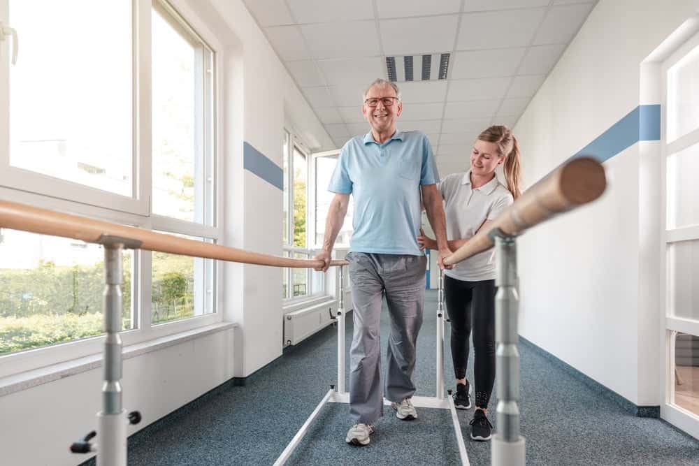 A female therapist teaching a senior man to regain his walking ability