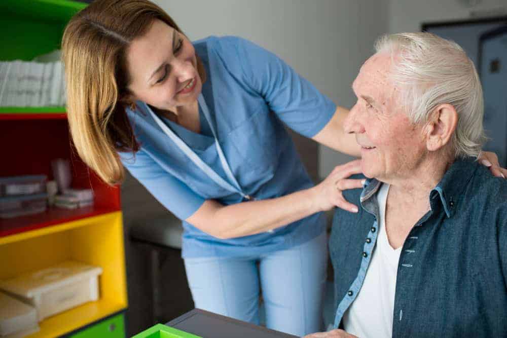 a happy in-home caregiver assisting a senior at his home