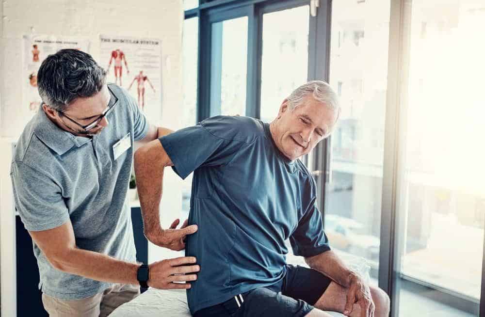 senior man using physical therapy to treat back pain