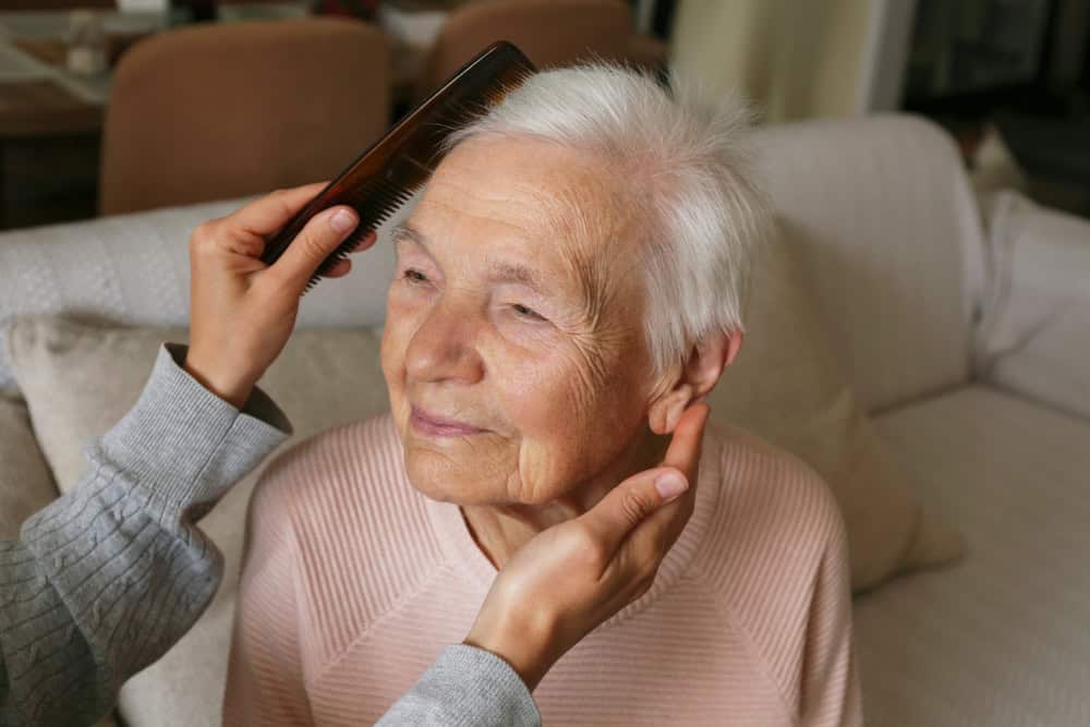 caregiver brushing a senior woman’s hair in assisted living