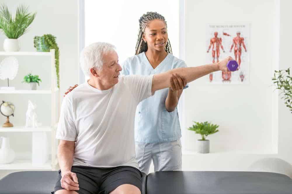 a physiotherapist helping an elderly man exercise with dumbbells