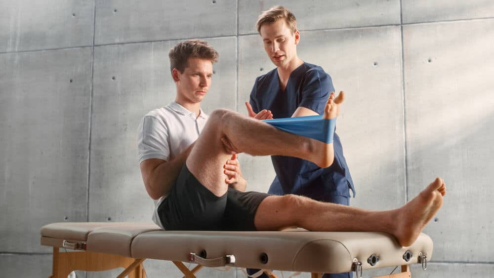 A physical therapist assisting an athlete after receiving an accreditation in physical therapy