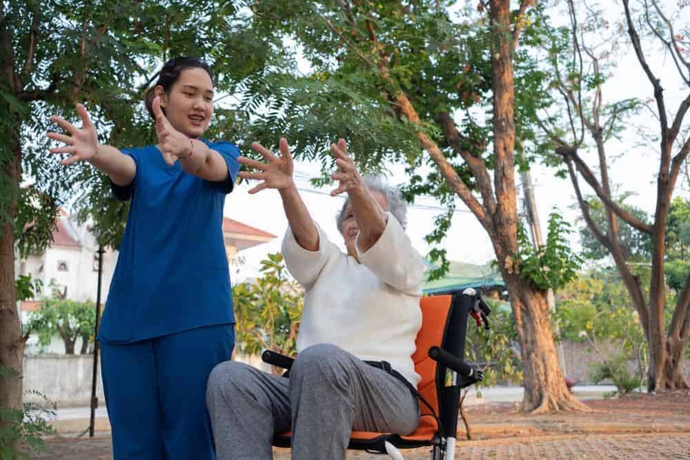 a physiotherapist helping an older woman with movement patterns