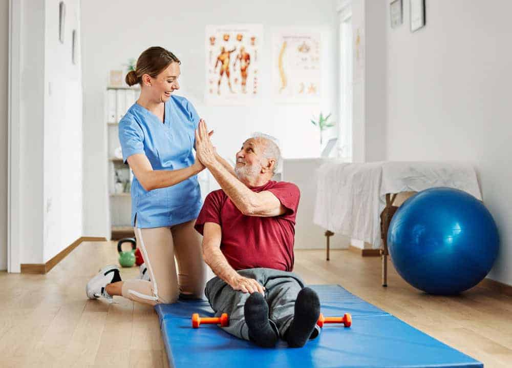 A female therapist giving a senior patient a high five. | manual therapy