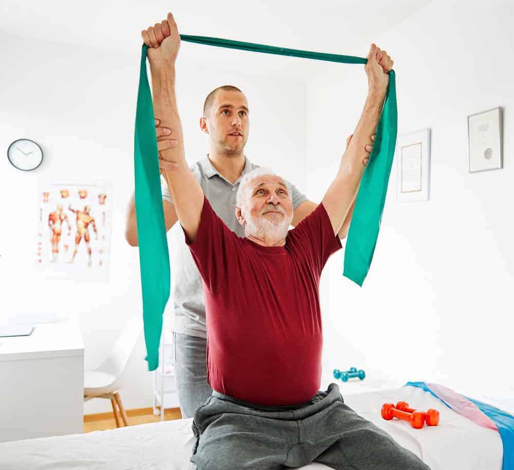 A male therapist helping a senior man do his stretches. | goal-oriented treatment