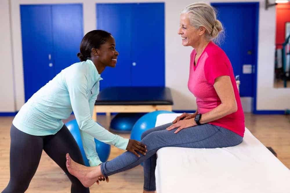 A female therapist giving a leg massage to an older lady | best care possible