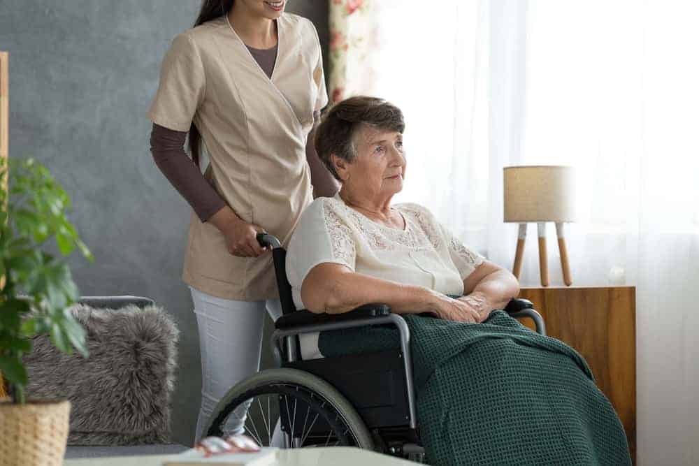 senior lady with dementia sitting in a wheelchair receiving care from a nursing facility