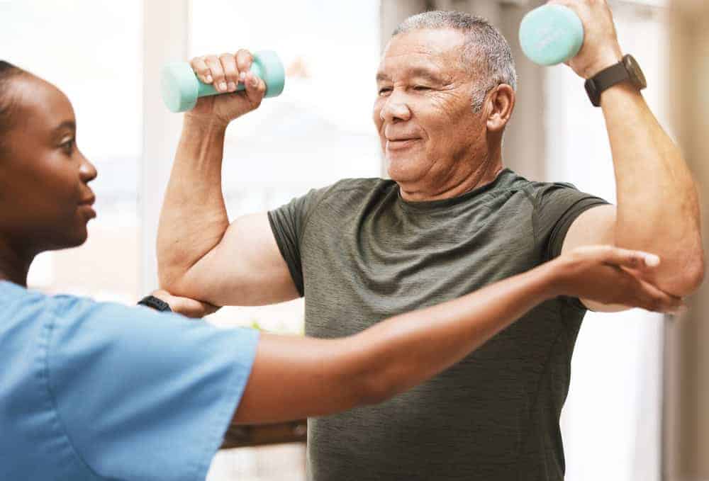 Physical therapy is beneficial for older adults - elderly man performing a physical activity with dumbbells