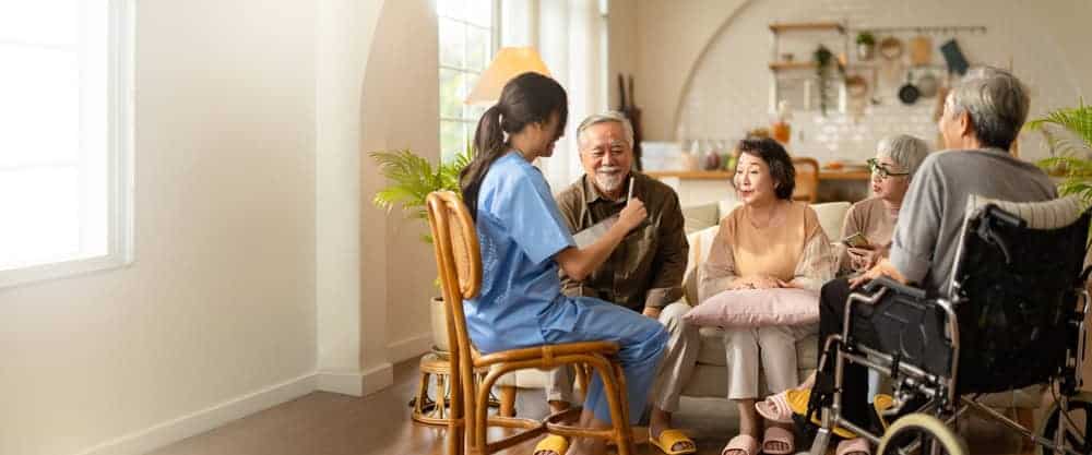 A therapist talking to a group of older people in an assisted home.