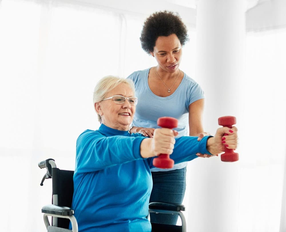 A physical therapist helping a senior exercise.