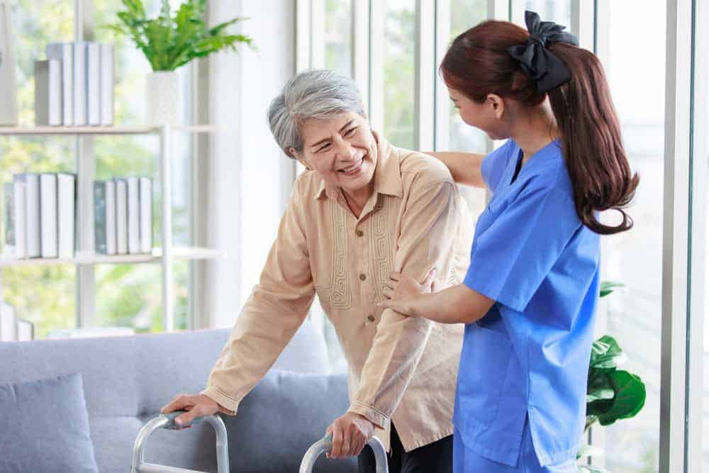 A female therapist assisting an old woman in a walker