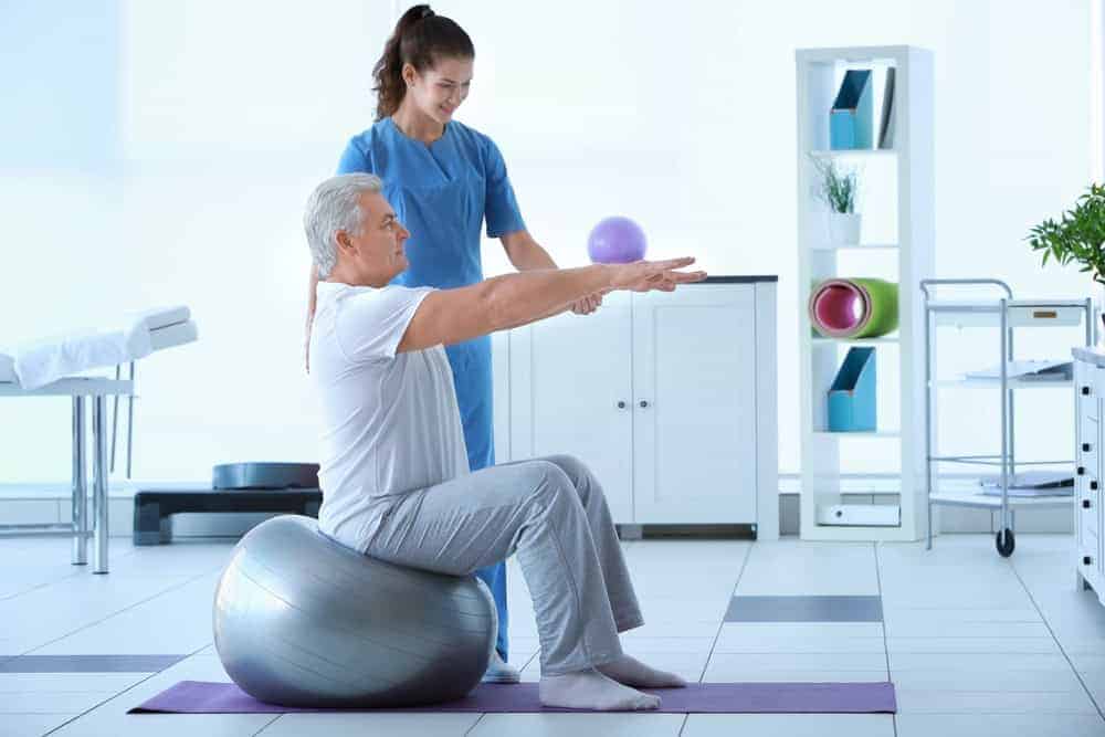 A female therapist teaching a senior man how to exercise safely