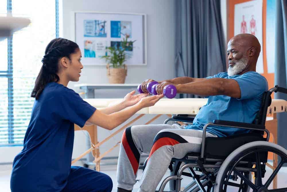 a physiotherapist assisting a senior with his exercises/ respected fitness