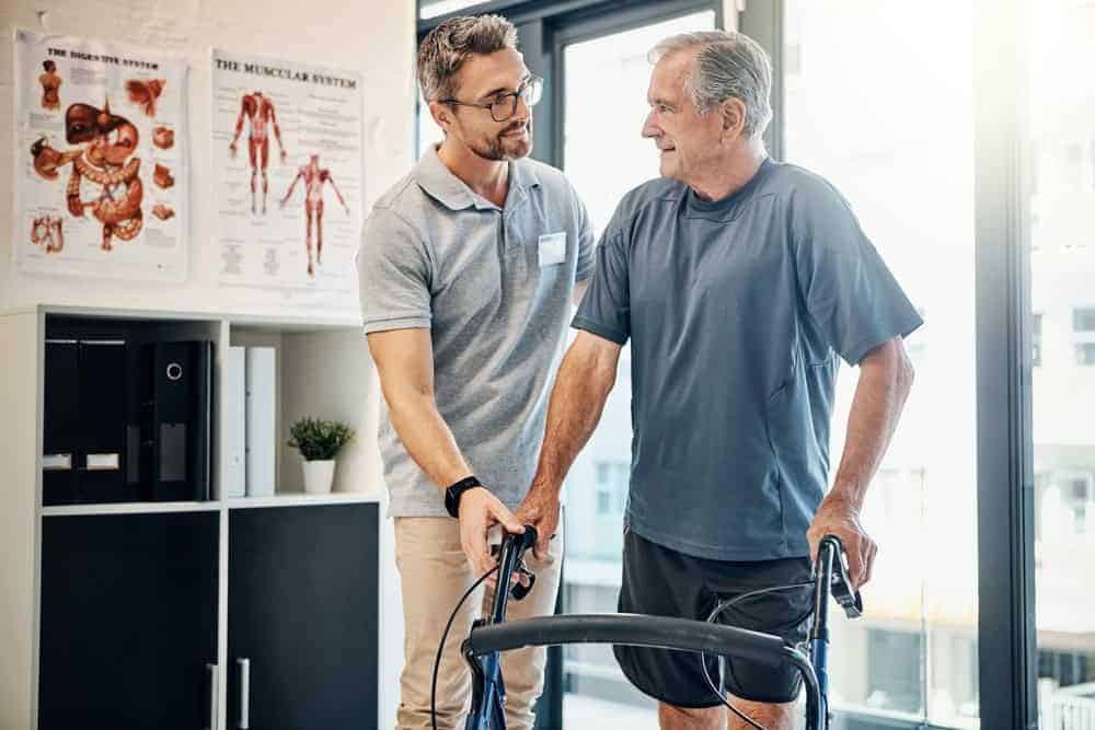 a physical therapist assisting an older man with his rehabilitation at a private practice