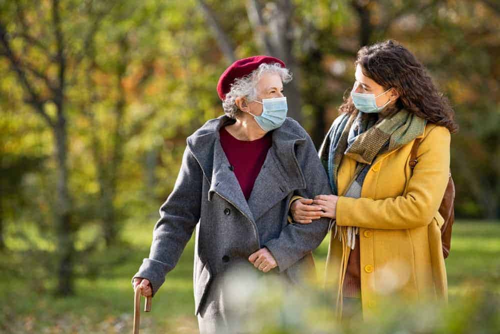 a staff at a memory care home assisting an older woman taking her evening walk