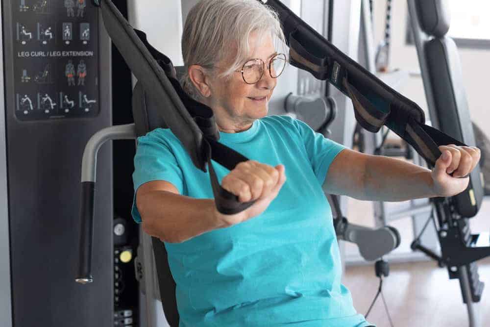 kinesiologist supervising older woman weight-lifting