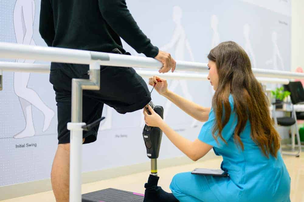 A therapist adjusting the prosthetic leg of a person living with a disability