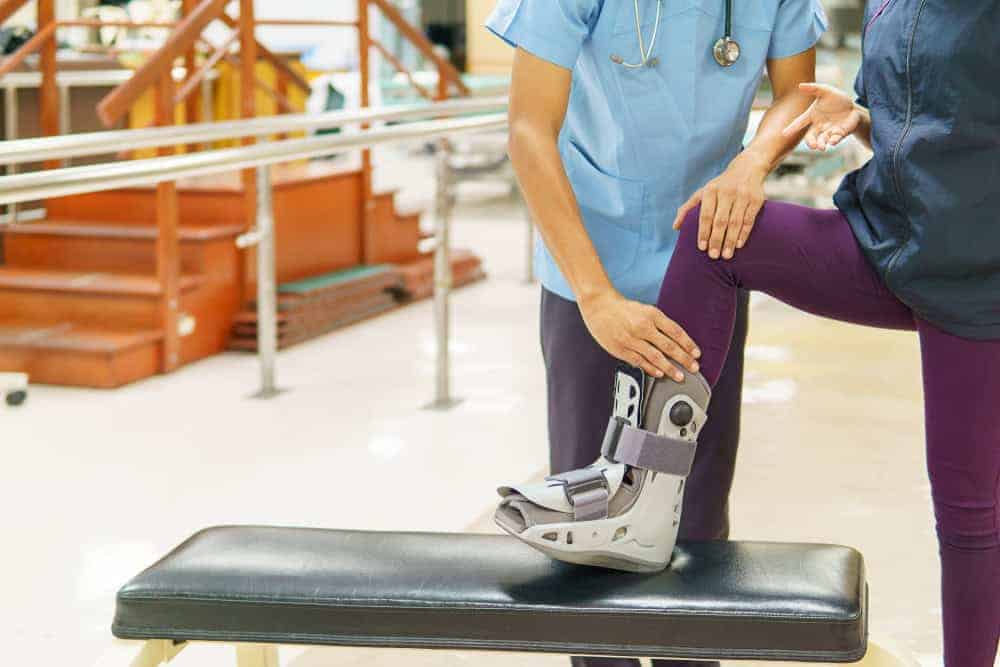 Physical therapist helping senior wearing orthopedic boot - physical therapy program