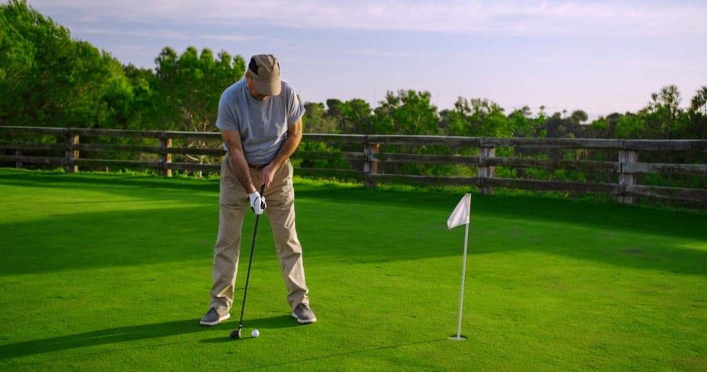 Older man playing golf at home - indoor activities for seniors during lockdown