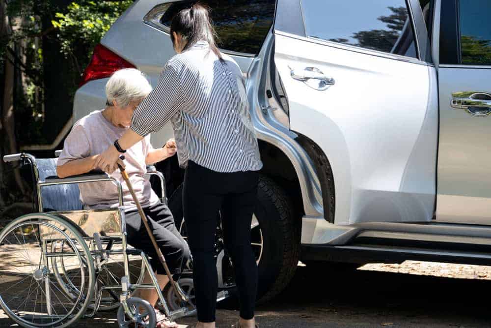 A female caregiver assisting a senior woman getting out of the car - private elderly care