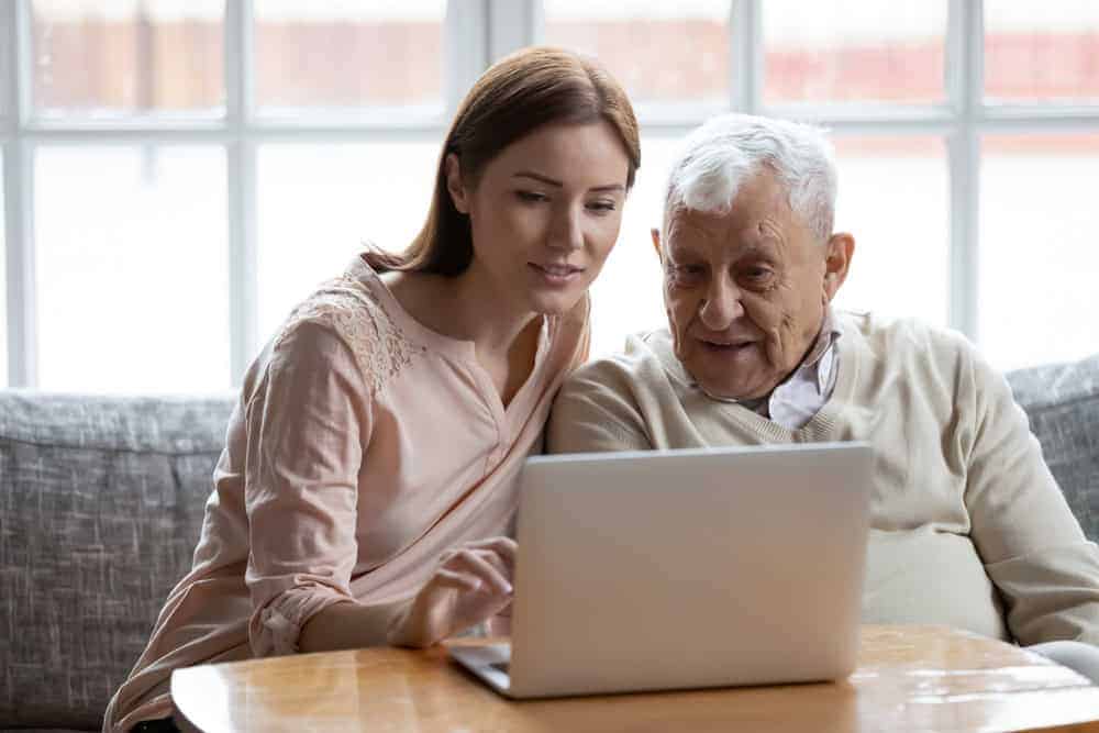 A daughter and his senior father using a laptop to search online - dementia caregiver resources