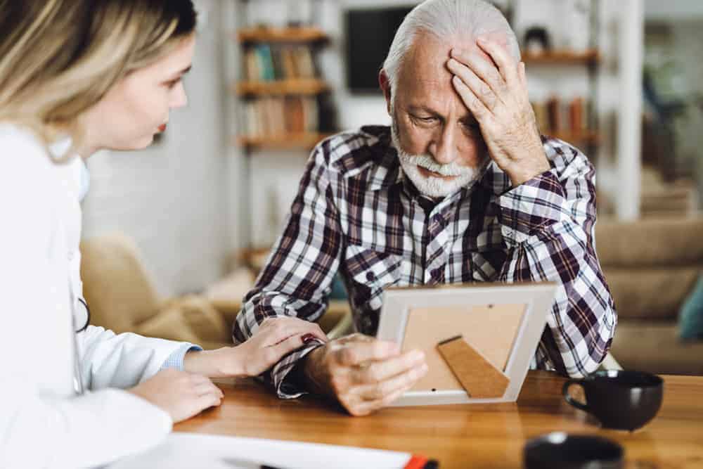 Elderly man with dementia trying to recall a photograph - forms of dementia