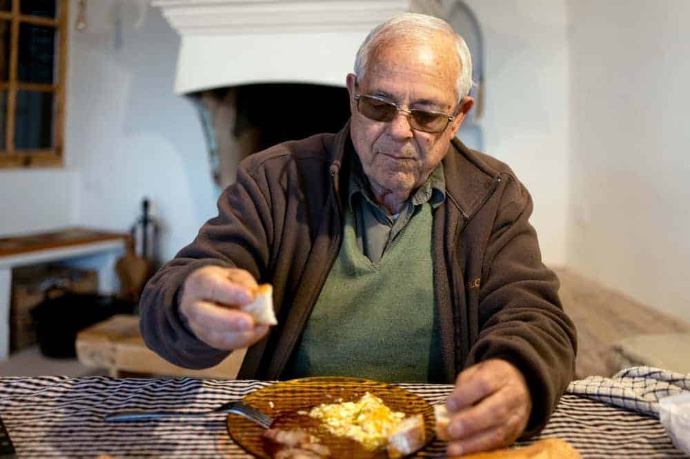 elderly man eating in a memory care facility | how much is a memory care facility