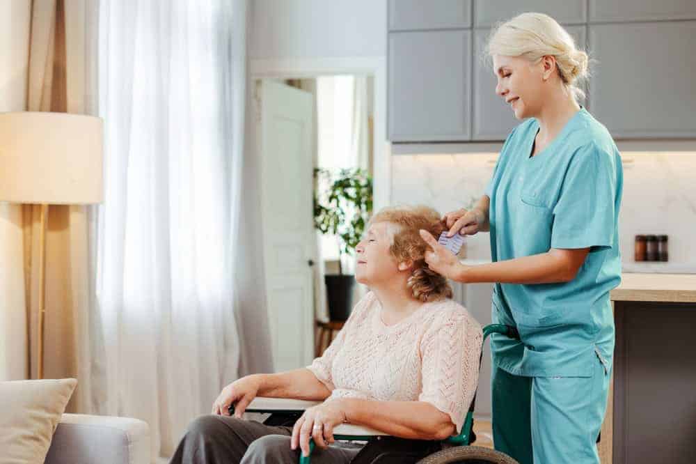 caregiver brushing the hair of a senior woman in an independent assisted living home