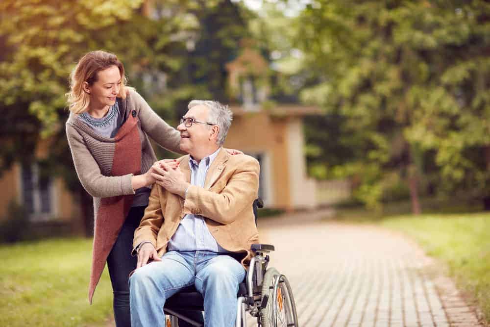 a middle-aged woman and a senior gentleman being affectionate in the garden - 24-hour senior care