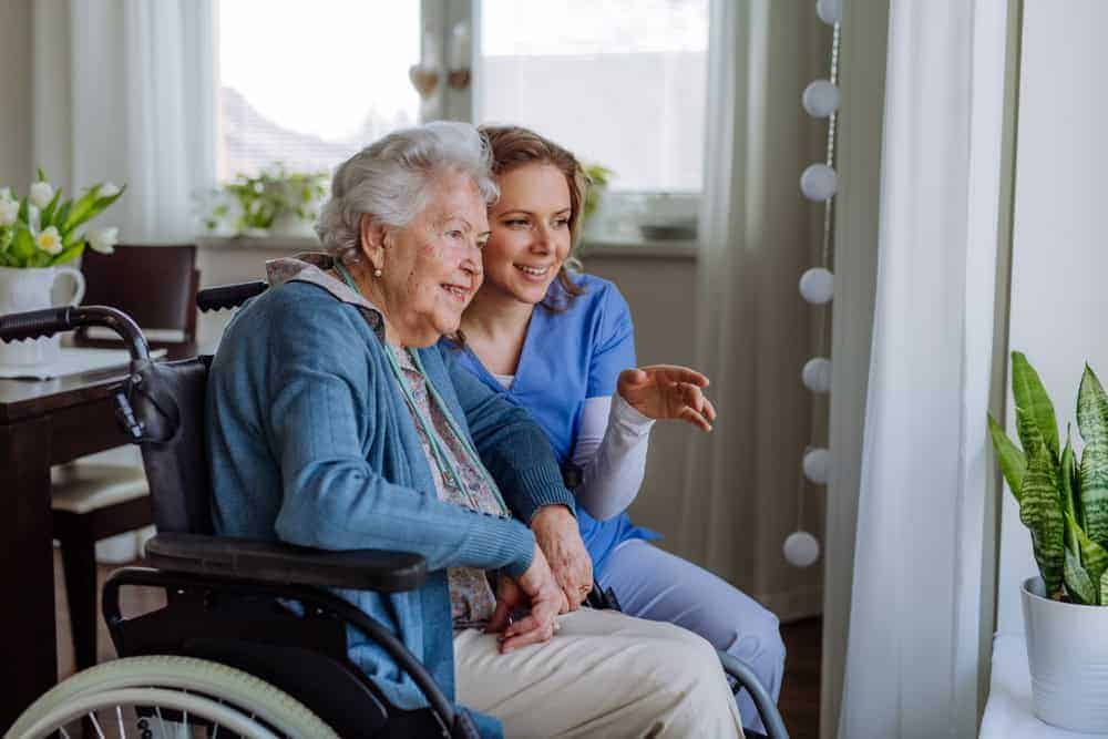 a senior and her caregiver looking at a plant and discussing it - 24-hour live-in care