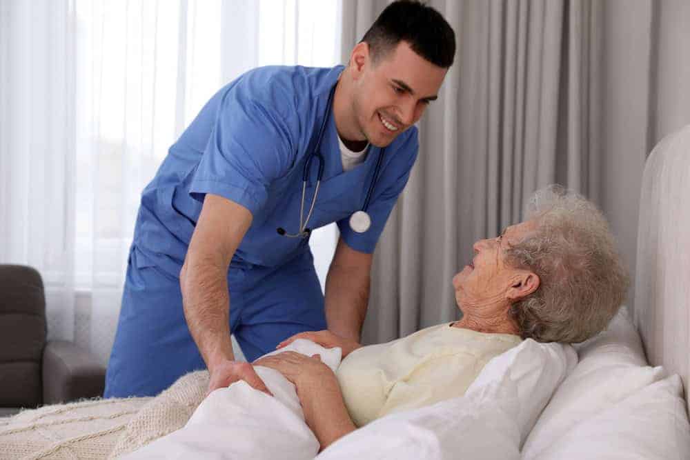 a nurse tucking in bed an aging woman - 24-hour home care at home