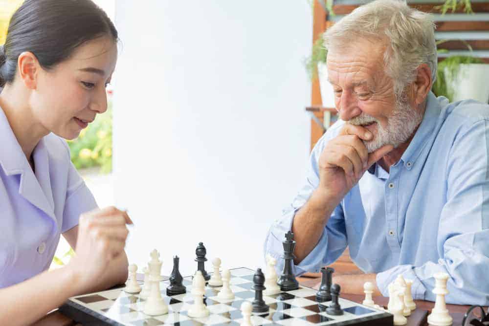 caregiver helping senior enjoy their hobby - chess