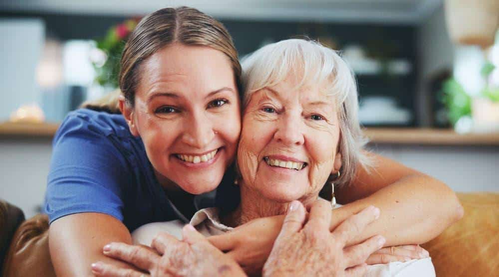 a young caregiver sharing a light moment after helping an older woman with dressing at a long term care facility