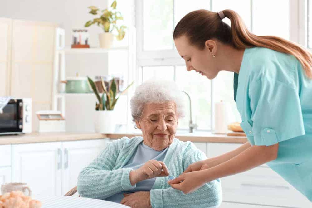 Female home health aide helping a senior woman with medications