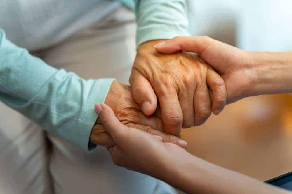 older woman holding hands of her caregiver - Medicaid for home health care