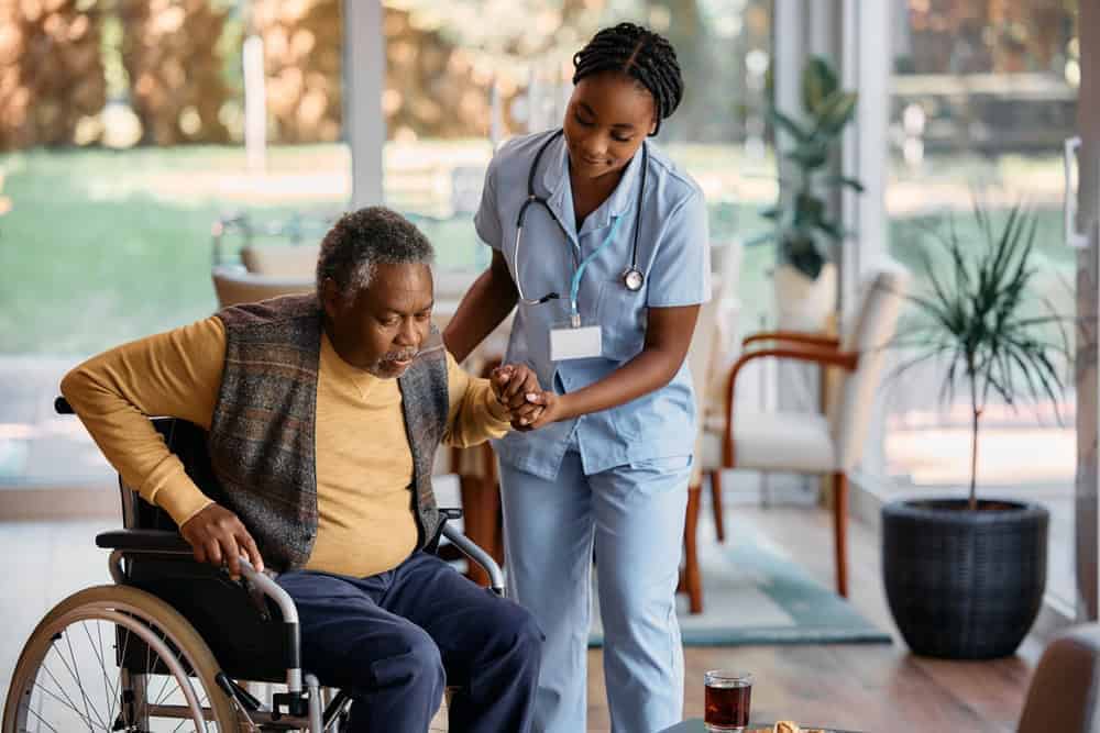 female caregiving helping an elderly man from a wheelchair - private senior care homes