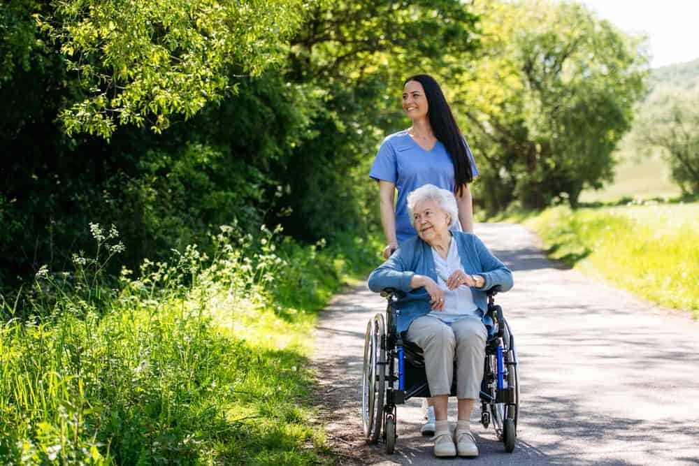 Caregiver pushing an older woman in a wheelchair - care at home agency