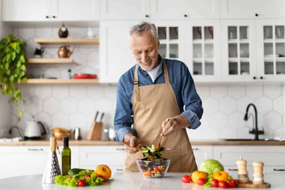 a happy grandfather enjoying preparing a healthy meal | home caretaker services