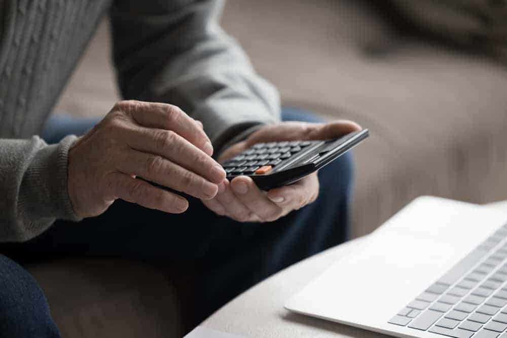 A close-up, crop view of a senior’s hand holding a calculator - 24-hour in-home care cost