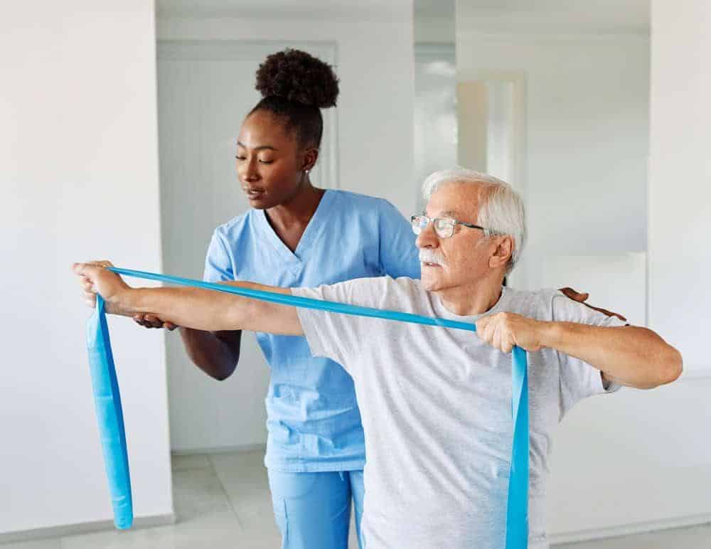 a physiotherapist helping an older man with his physical therapy at a skilled nursing home